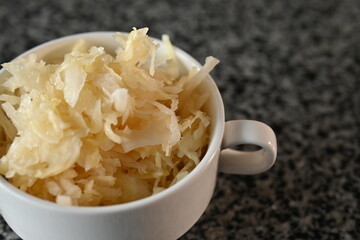 fermented cabbage, fermented white cabbage in a white plate on a gray background