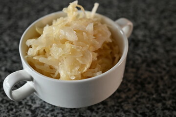 fermented cabbage, fermented white cabbage in a white plate on a gray background