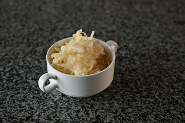 fermented cabbage, fermented white cabbage in a white plate on a gray background