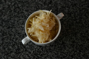fermented white cabbage in a white plate on a gray background