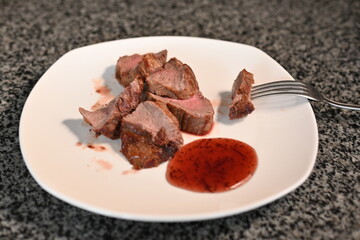 veal steak roasted medium rare in used dishes with red sauce 