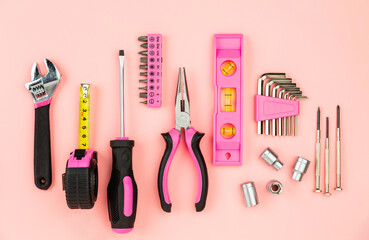Renovation tools for a girl. Men's work is done by woman's hands. Strong, but beautiful. Pink construction equipment  on pink background. Woman's or girl's power.  Top view flat lay