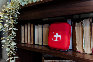 Home first aid kit stands among books, health care concept.
