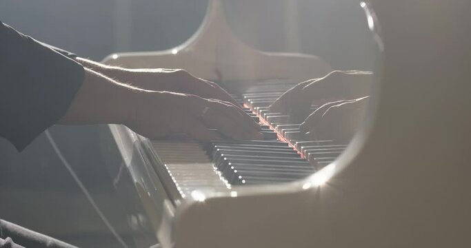 Male pianist plays grand piano in a music studio. Pianist plays beautiful grand piano, touches piano keys. Hands close-up, slow motion