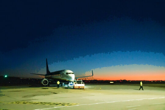 Airport of Memmingen - tractor pushes an airplane and technicians