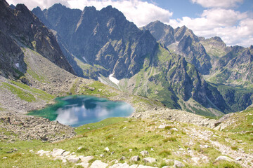 Widok w Dolinie Białej Wody na jezioro Litworowy Staw wysokogórski ukazujący szczyty w Tatrach podobne do Alp.