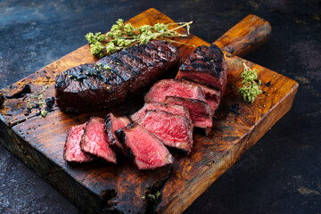 Barbecue dry aged angus roast beef steak with herb butter and dried oregano served as close-up on a rustic cutting board with copy space - obrazy, fototapety, plakaty