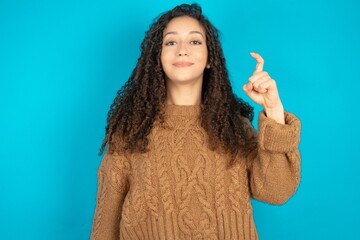 beautiful teen girl wearing brown knitted sweater pointing up with fingers number nine in Chinese...