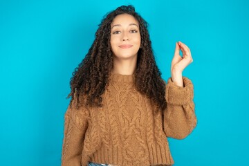 beautiful teen girl wearing brown knitted sweater pointing up with hand showing up seven fingers...