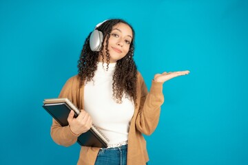 Positive beautiful caucasian teen girl wearing brown sweater advert promo touch finger teeth