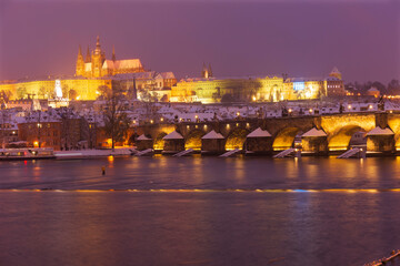 Night colorful snowy Christmas Prague Lesser Town with gothic Castle and Charles Bridge, Czech republic