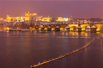 Night colorful snowy Christmas Prague Lesser Town with gothic Castle and Charles Bridge, Czech...