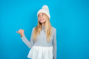 Charming Teen caucasian girl wearing blue knitted sweater and woolly hat looking at copy space...