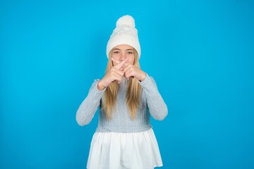 Teen caucasian girl wearing blue knitted sweater and woolly hat Has rejection angry expression...