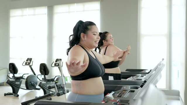 Two chubby women doing a stretching and little chat on a treadmill before start running.