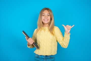 Beautiful kid girl wearing yellow sweater holding notebook showing up number six Liu with fingers gesture in sign Chinese language