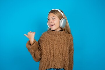 beautiful caucasian teen girl wearing brown sweater listens audio track via wireless headphones...