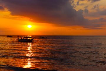 Scenic view of dramatic sunset in the beach with silhouette boats on the sea
