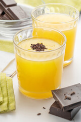 Orange juice in a fluted glass with dark chocolate pieces and chocolate chips.