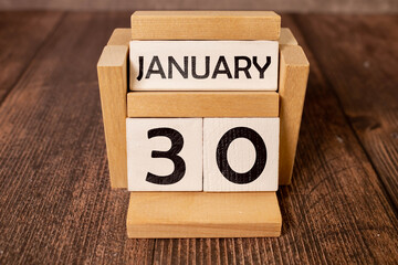 Cube shape calendar for January 30 on wooden surface with empty space for text.