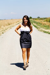 Young Caucasian Teen Woman Standing In Dress On Gravel Road