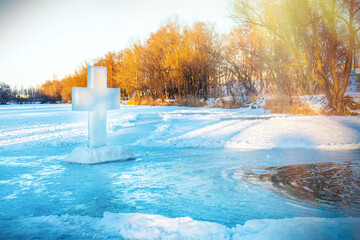 Christian symbol of the cross, made of a block of ice on the ice near an ice hole in a frozen lake...