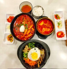 Set of korean food on the table which is Bibimbap, Topokki, Soondubu Jigae and side dishes