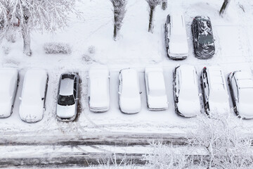 Cars covered first snow on parking after snowfall and blizzard. Cold snowy weather