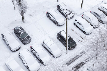 Cars under snow on a street parking after snowfall and blizzard. Car covered snow, cold snowy weather