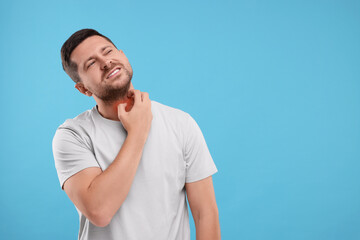 Allergy symptom. Man scratching his neck on light blue background. Space for text