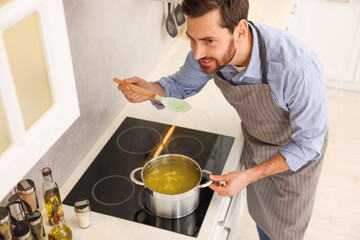 Man cooking delicious chicken soup in kitchen, above view