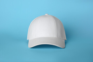 Stylish white baseball cap on light blue background