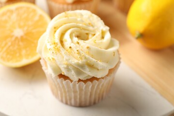 Tasty cupcake with cream, zest and lemons on board, closeup