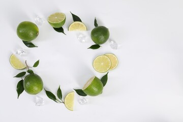 Frame of fresh limes, leaves and ice cubes on white background, flat lay. Space for text