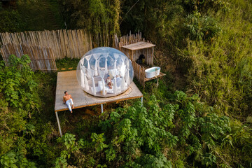 couple man and women in a bubble tent with an outdoor bathroom with bath in the jungle rainforest