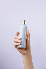 Cosmetic blue bottle on the woman's hand. Natural cosmetics concept. Mockup