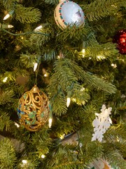 Close up view of a gold color retro style hanging filigree Christmas tree ornament on a Christmas tree background