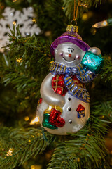 Macro view of a colorful retro style hanging glass Christmas tree ornament depicting a jolly snowman
