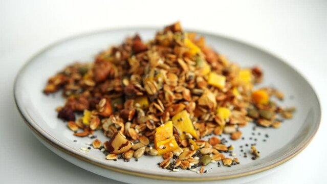 Healthy organic granola breakfast flakes with almonds, cashew nuts walnuts, hazelnuts, pumpkin seeds and cranberries circle rotation close up top view.