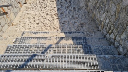 Steel stairs leading down to the sand and sea