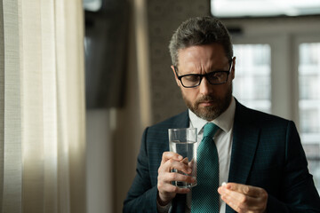 Man taking a Medicine pill from headache migraine. Business man in suit uses a laptop, is tired got headache migraine. Headache pain concept. Painful men are stressed at work in office.