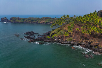 Naklejka premium Aerial top view on tropical beach with green palm trees under sunlight Drone view in Goa