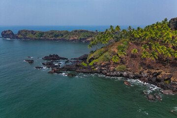 Aerial top view on tropical beach with green palm trees under sunlight Drone view in Goa