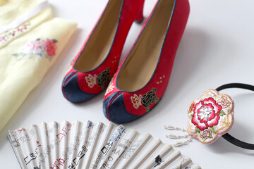 Traditional Korean gomusin or danghye shoes, a traditional jeogori hanbok top, a buchae traditional fan and a traditional hanbok hairband.