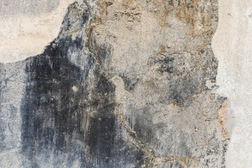 old concrete wall with black paint leftovers covered with whitewash stains, full-frame background and texture.