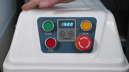 A close-up of the chef turns on a large industrial food processor for kneading burger dough in the restaurant kitchen, he presses the power button. A timer is turned on on the combine.