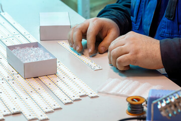 Close-up of a worker installing lenses on the diode strips of a lamp.