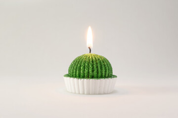 A lighted green wax candle burning isolated on white background