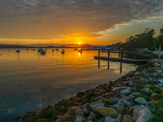Aerial sunrise over the water with boats and clouds