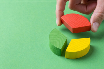 Colorful wooden pie chart pieces, hand adding piece of diagram